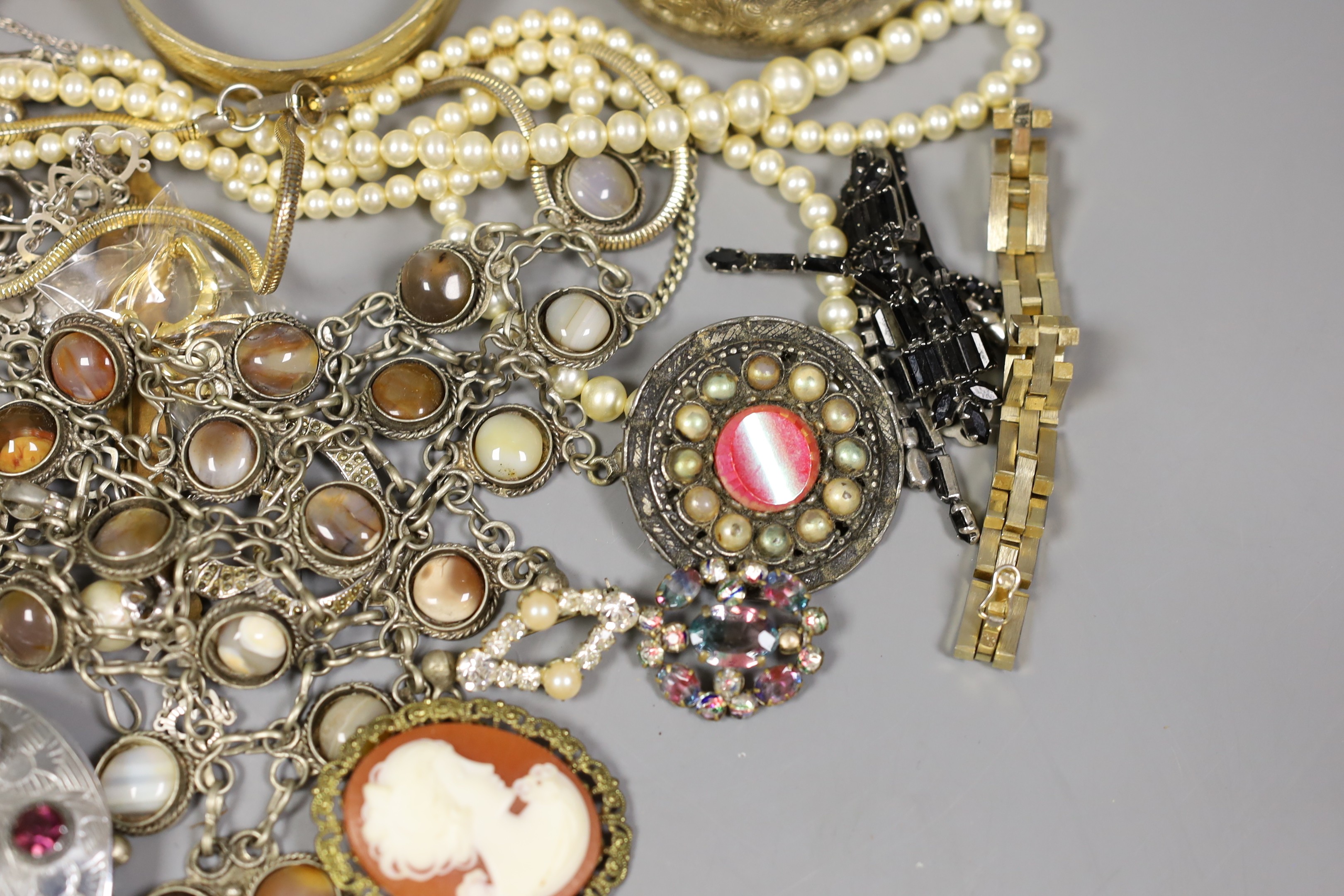 Assorted costume jewellery including a silver charm bracelet, hung with various charms including merry-go-round and bull.